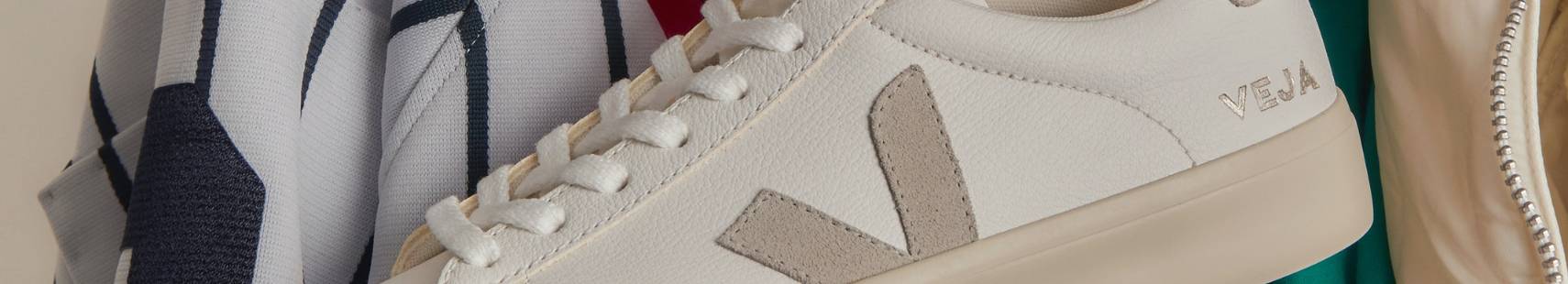 Zapatilla Veja blanca con logo lateral en ante y fondo de ropa deportiva